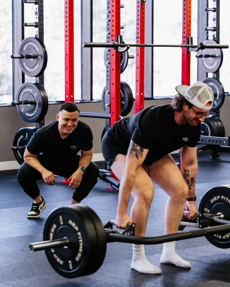 Dr. Edward Benitez coaching a patient through a barbell deadlift at Overtime Sports PT in Centennial, CO